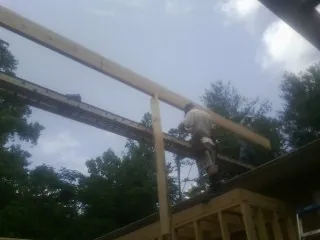 Carpenter setting a ridge beam over a new addition frame — Ice Dam Removal by Roofing Brothers in Ooltewah
