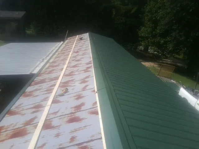 Old rusted panels beside newly installed green metal roofing — Wind Damage Roof Repair by Roofing Brothers in Ooltewah