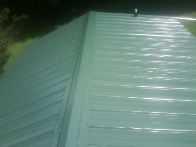 New green metal panels meeting at the ridge of a roof — Flat Roof Repair work by our crew in Ooltewah