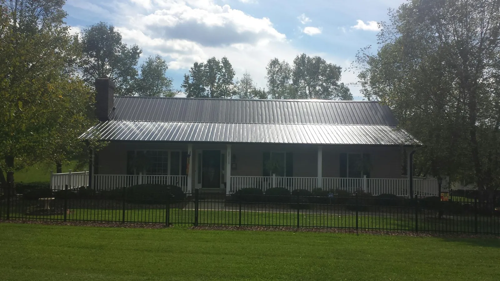 Gray metal roof on a brick ranch with a full width front porch — Gutter Guard Installation work by our crew in Ooltewah