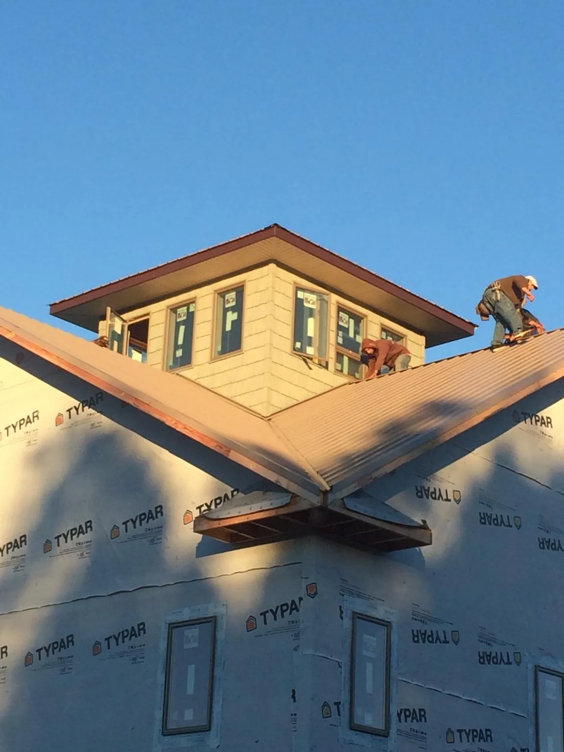 Roofers working around a rooftop cupola on a new metal roof at sunset — Roof Waterproofing in Ooltewah by Roofing Brothers